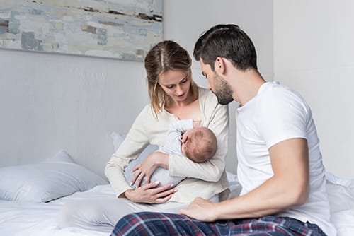 Mom breastfeeds baby as dad looks on